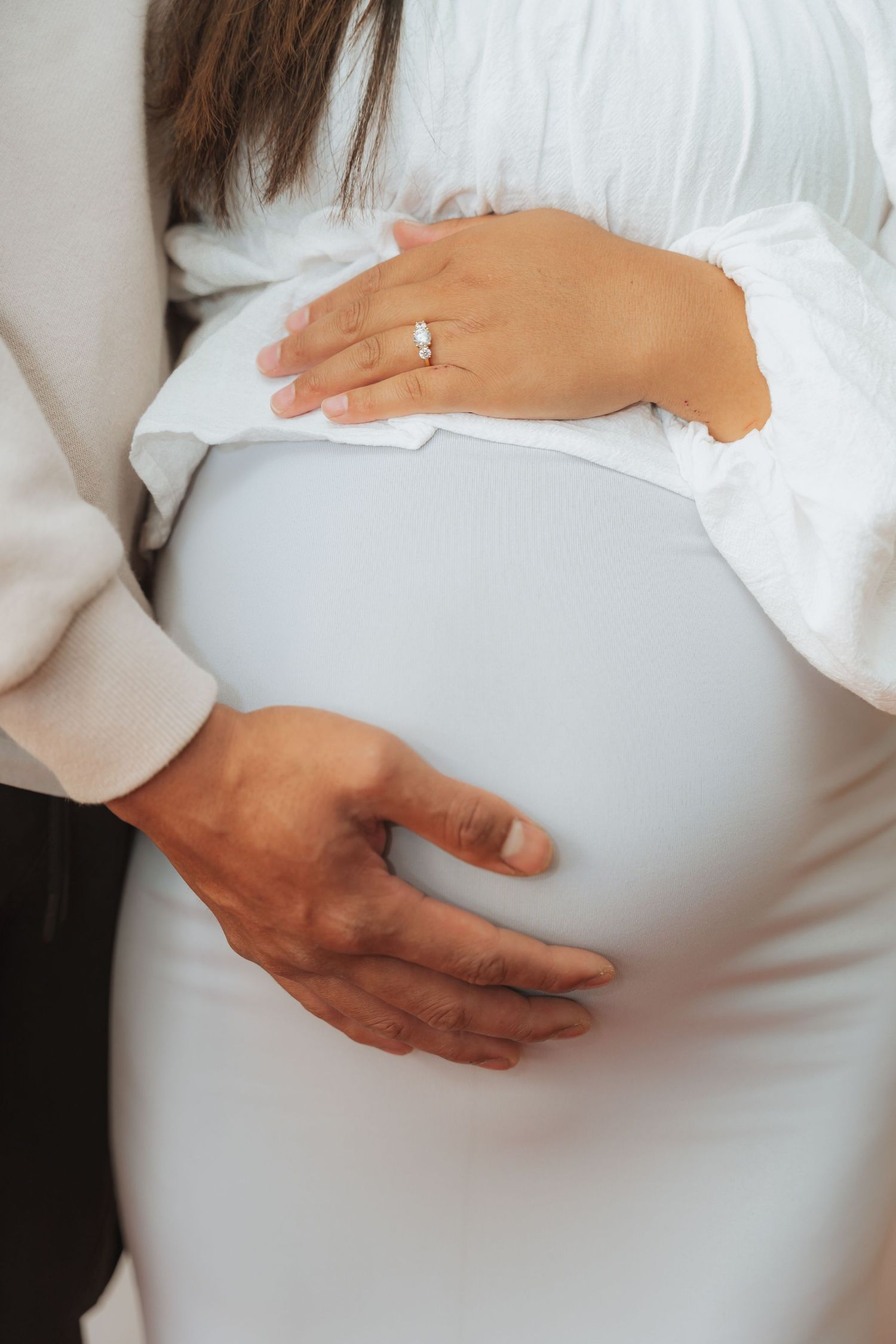 A series of photos showing hands gently cradling a pregnant belly in a white dress against a light background.