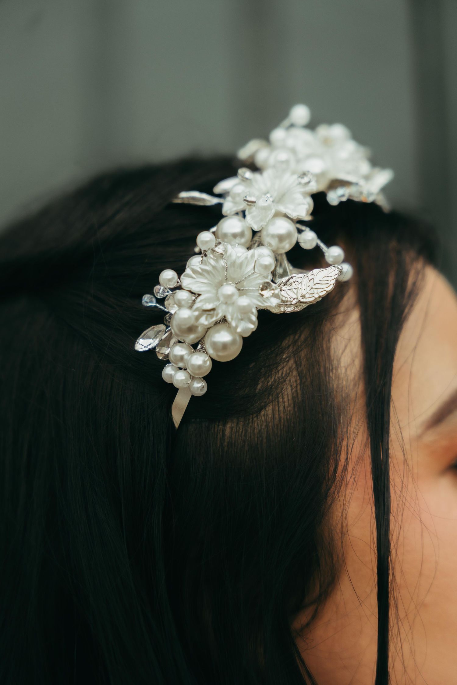 Elegant bridal hair comb adorned with pearl flowers and silver leaves on dark hair.