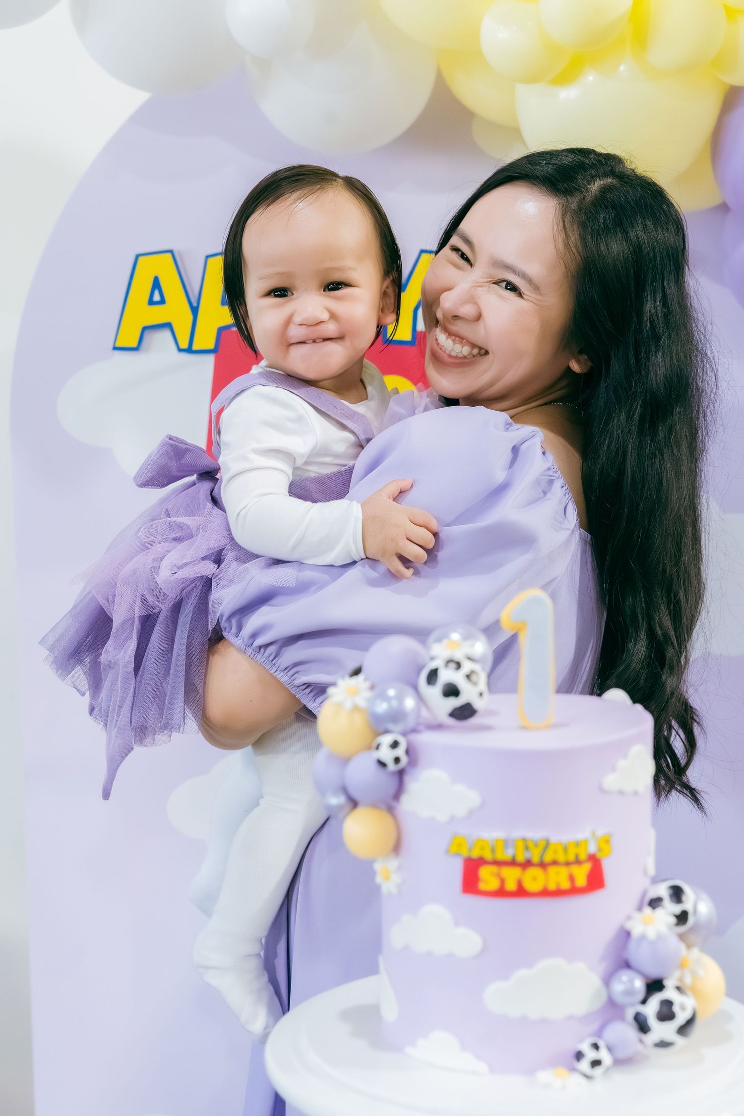 Celebration scene with purple decorations, stuffed animals and yellow balloons in the background.
