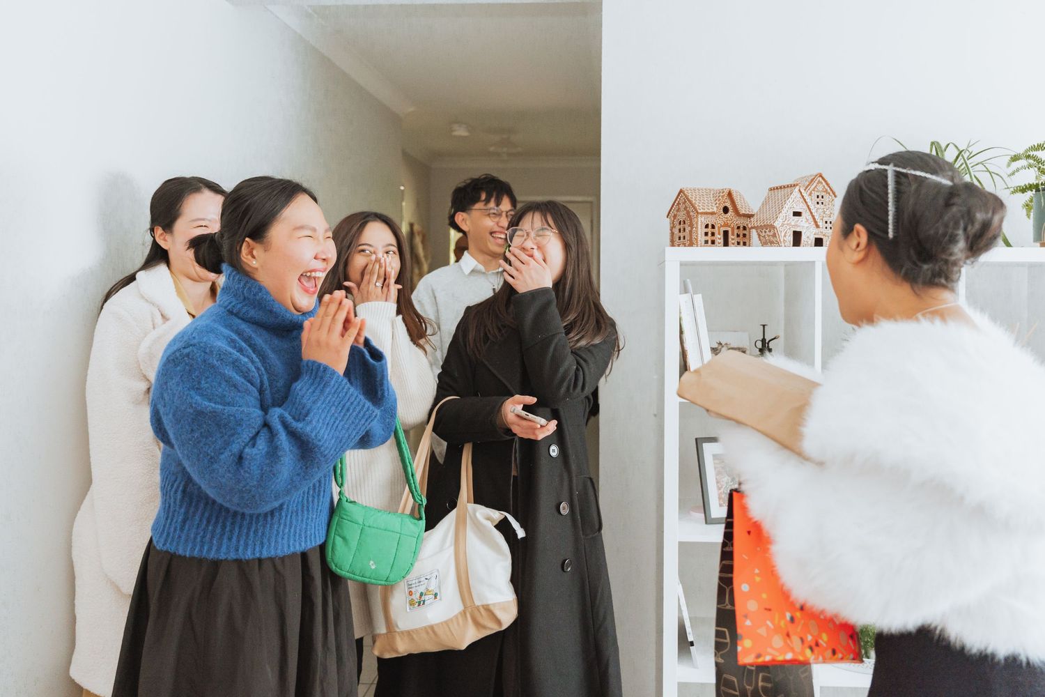 Joyful celebration with friends embracing and laughing together in a bright indoor setting.