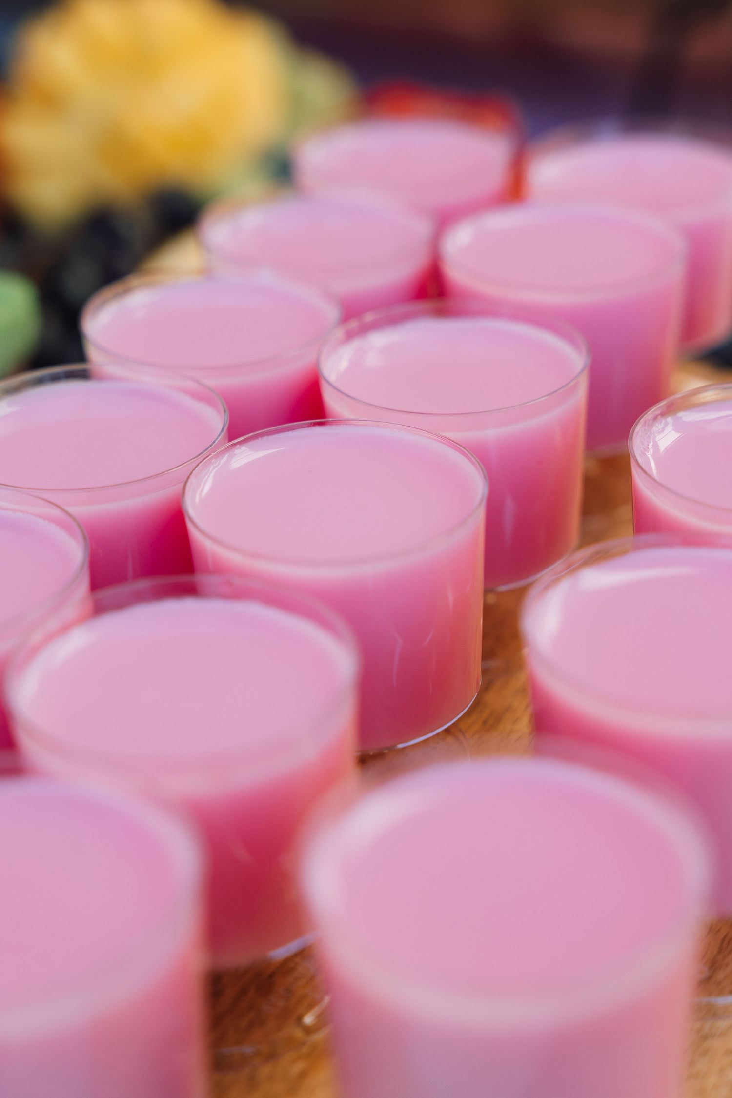 Pink jello desserts arranged in rows on a wooden surface create a repeating pattern of circular shapes.