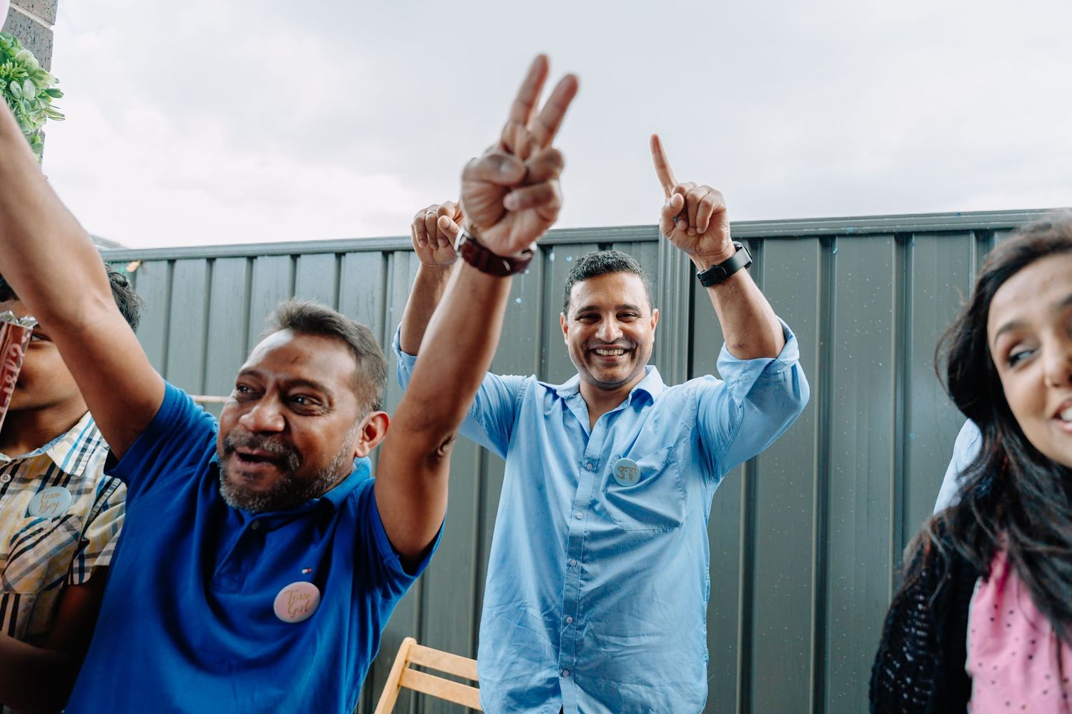 Celebratory moment captured with people raising their arms in excitement at an outdoor gathering.