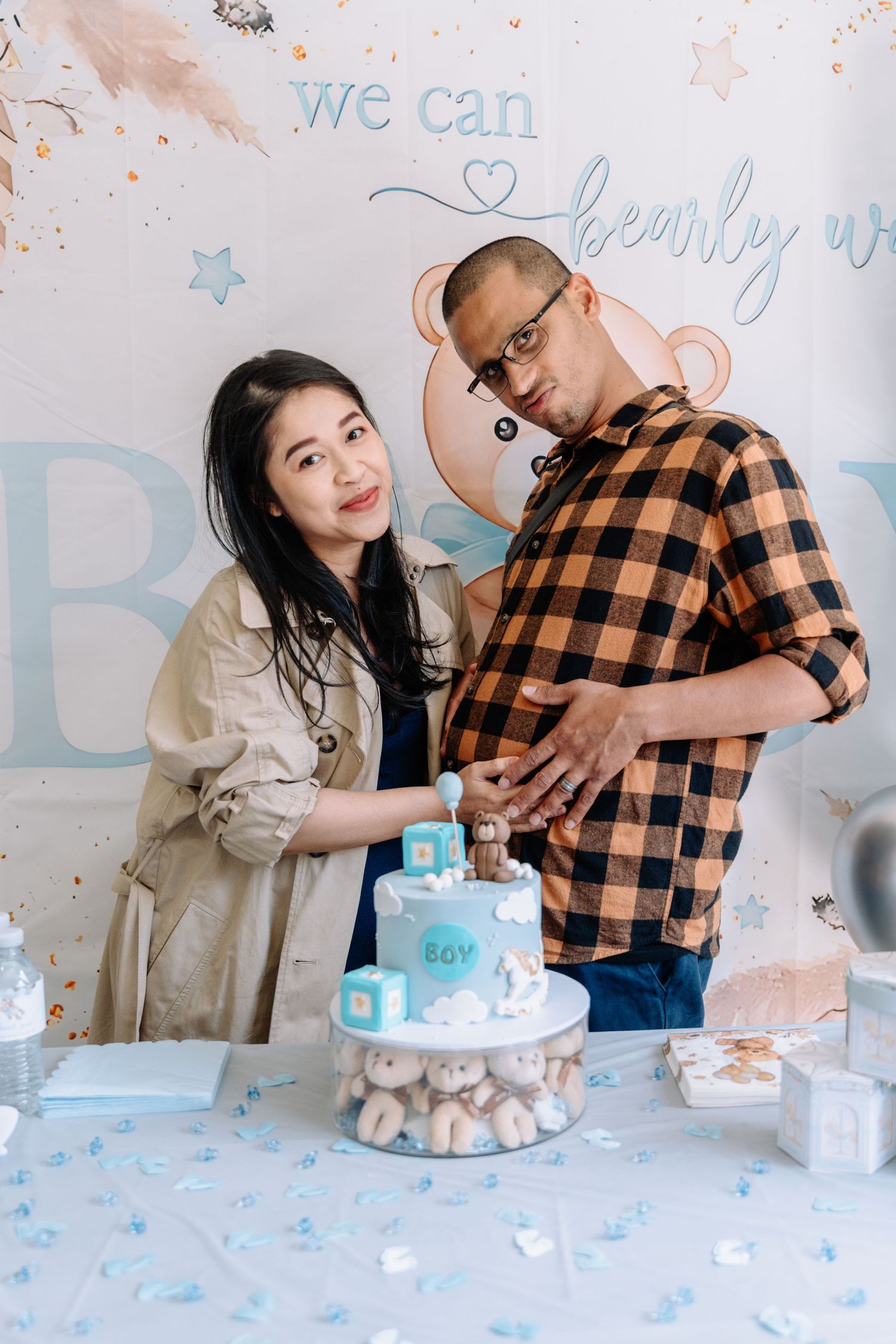 Gender reveal party setup with blue decorations and cake.