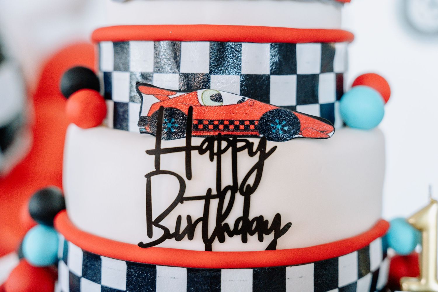 Decorative checkered pattern party banner with red accents and turquoise details for a racing themed birthday celebration.