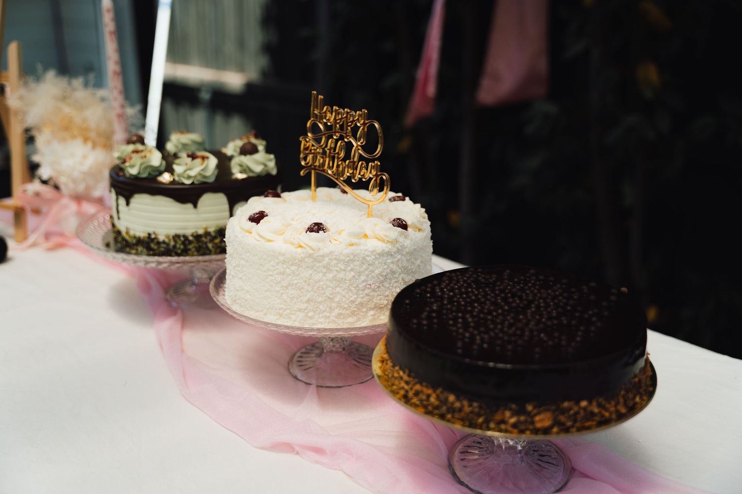 A row of elegant wedding cakes displayed on a table featuring various styles from white tiered to chocolate designs.