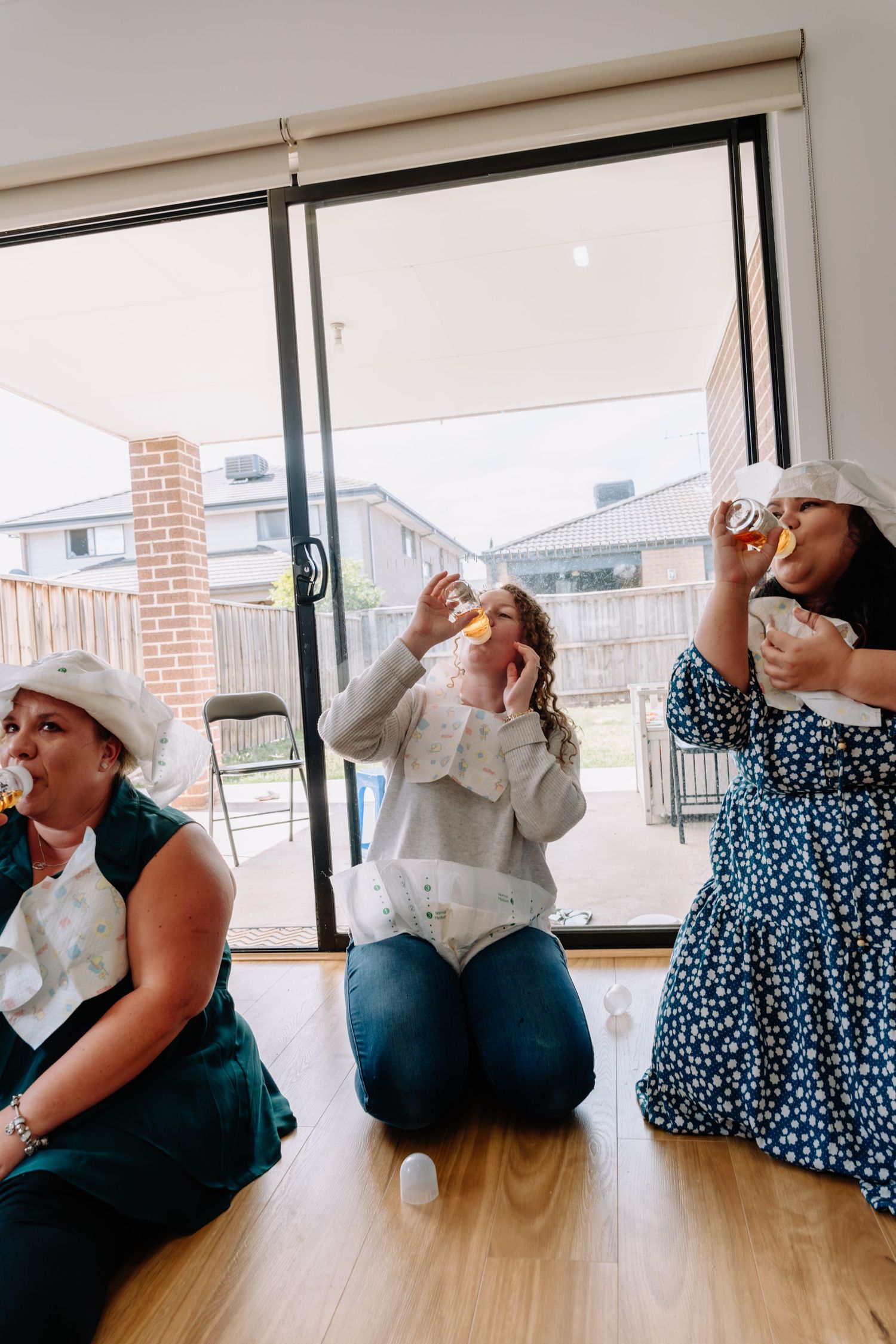A group of people in blue and white outfits perform dramatic poses while sitting on a hardwood floor near windows.
