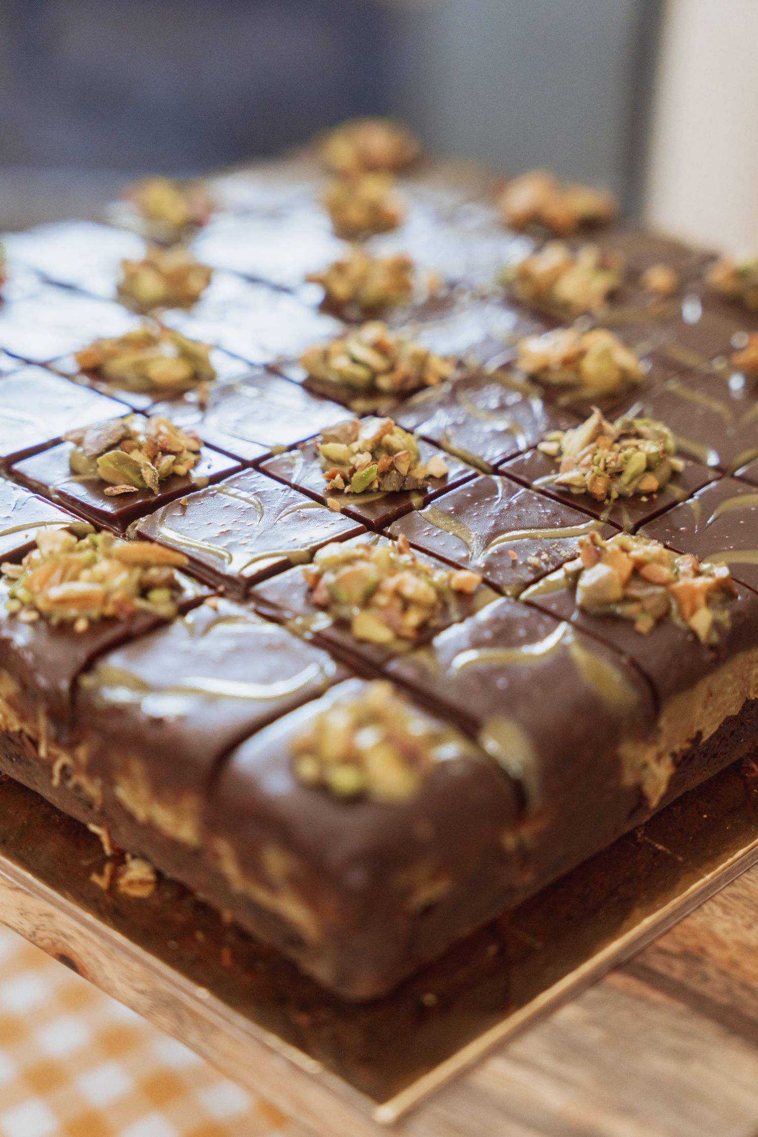 Homemade chocolate fudge squares topped with chopped walnuts arranged in rows on a wooden surface.