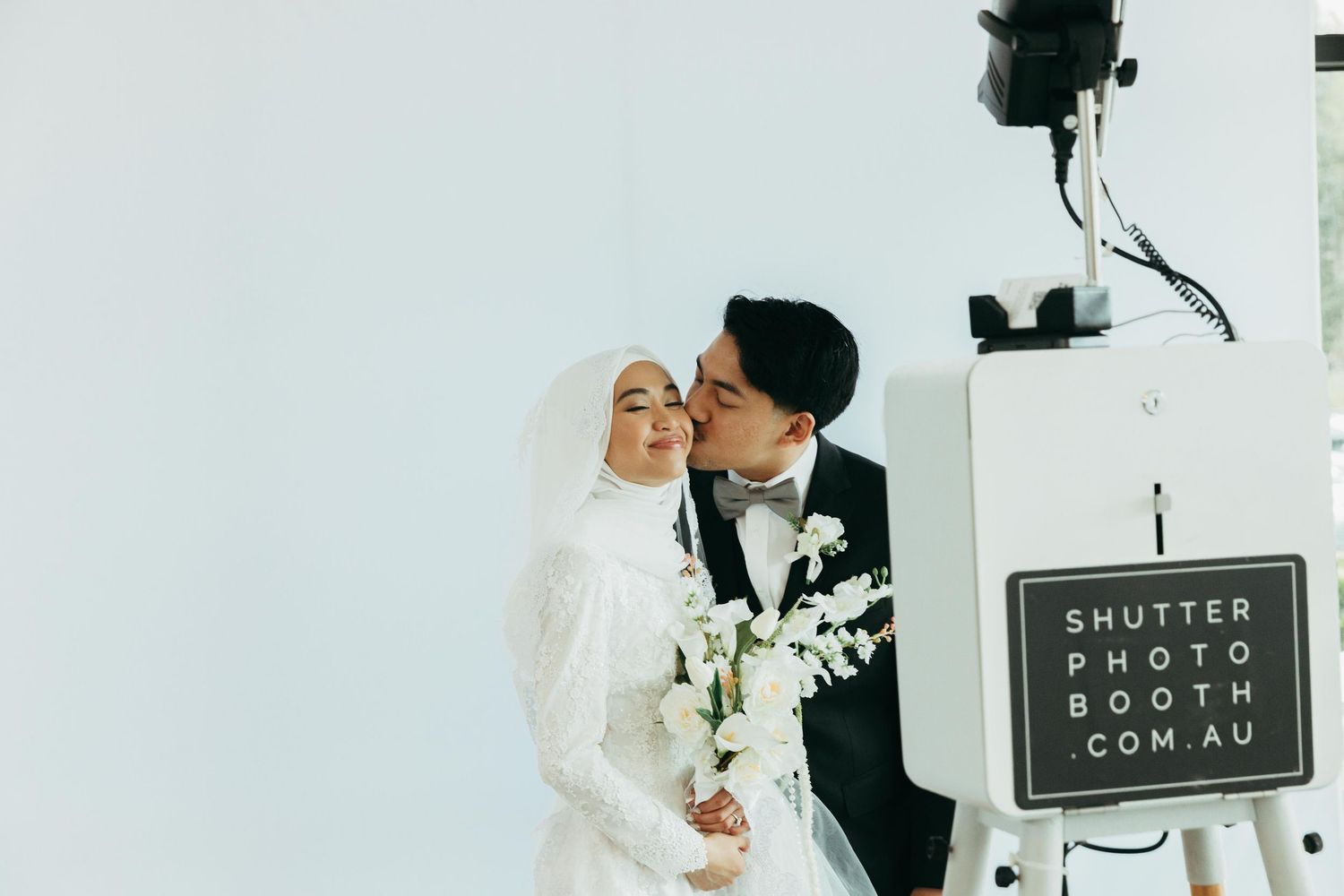 Muslim bride and groom posing at a photo booth at their wedding reception.