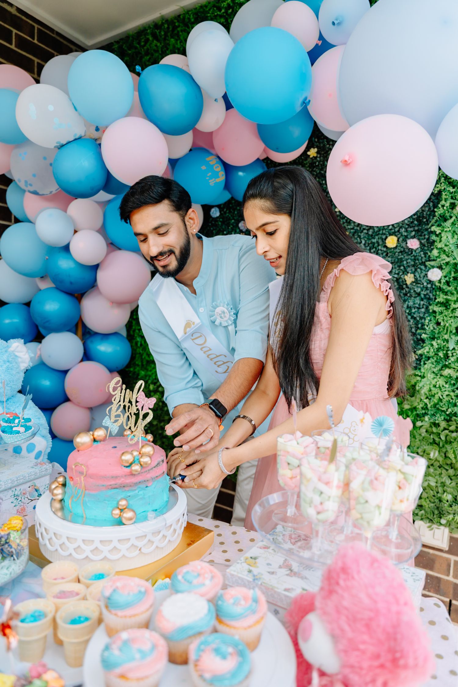 Gender reveal party dessert table with blue and pink ombre cake and coordinating treats.