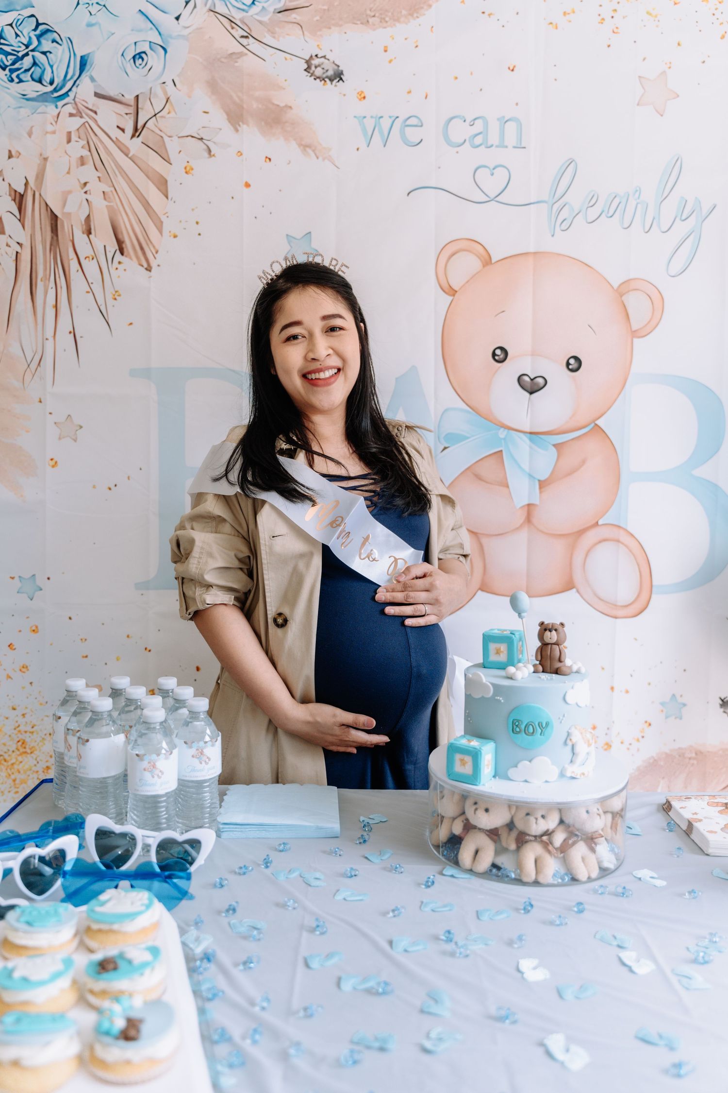 Baby shower party setup with teddy bear decorations, blue and white theme, and refreshments on display.