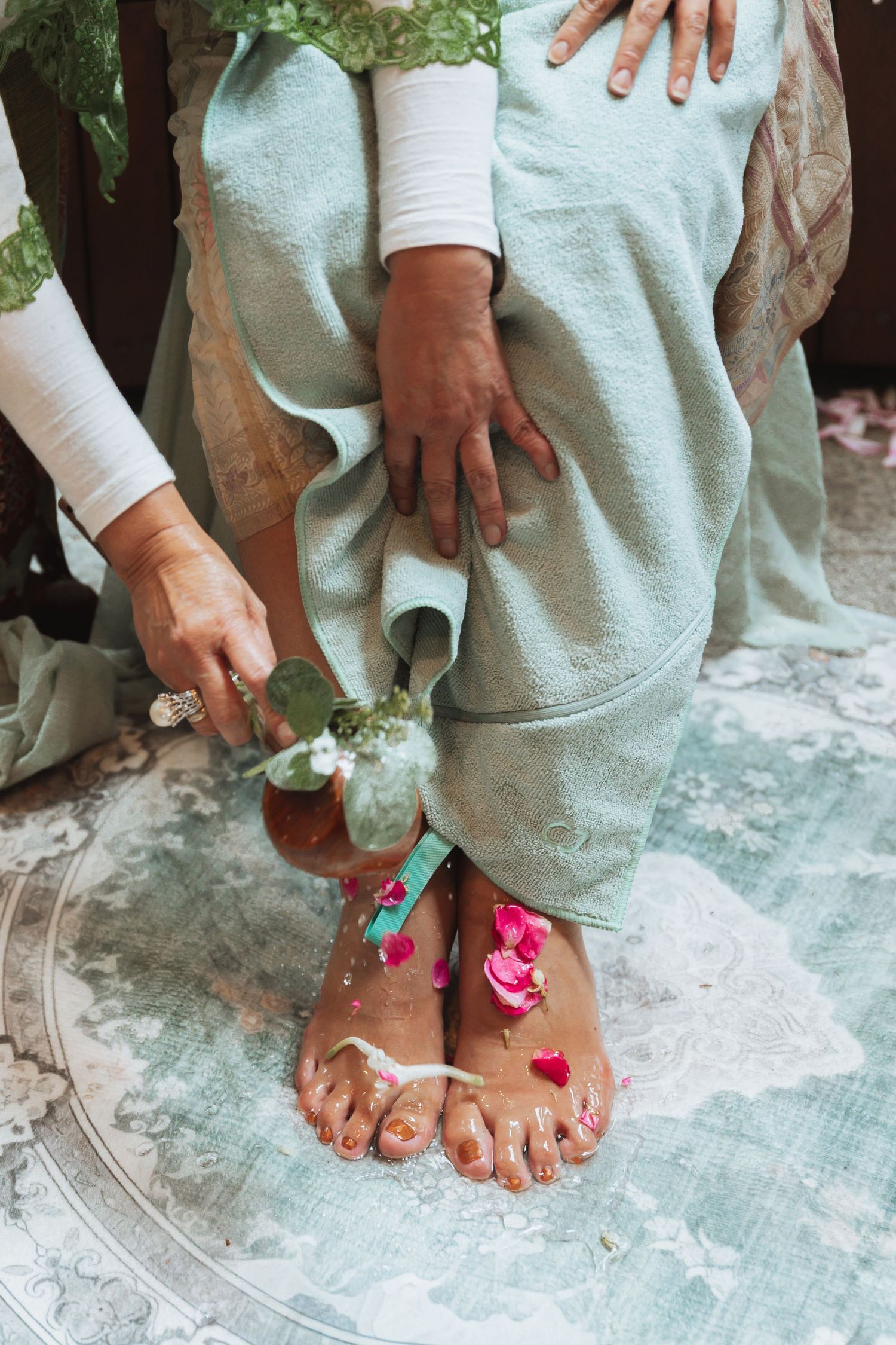 Close-up shots of feet decorated with pink flower petals against a light colored floor.