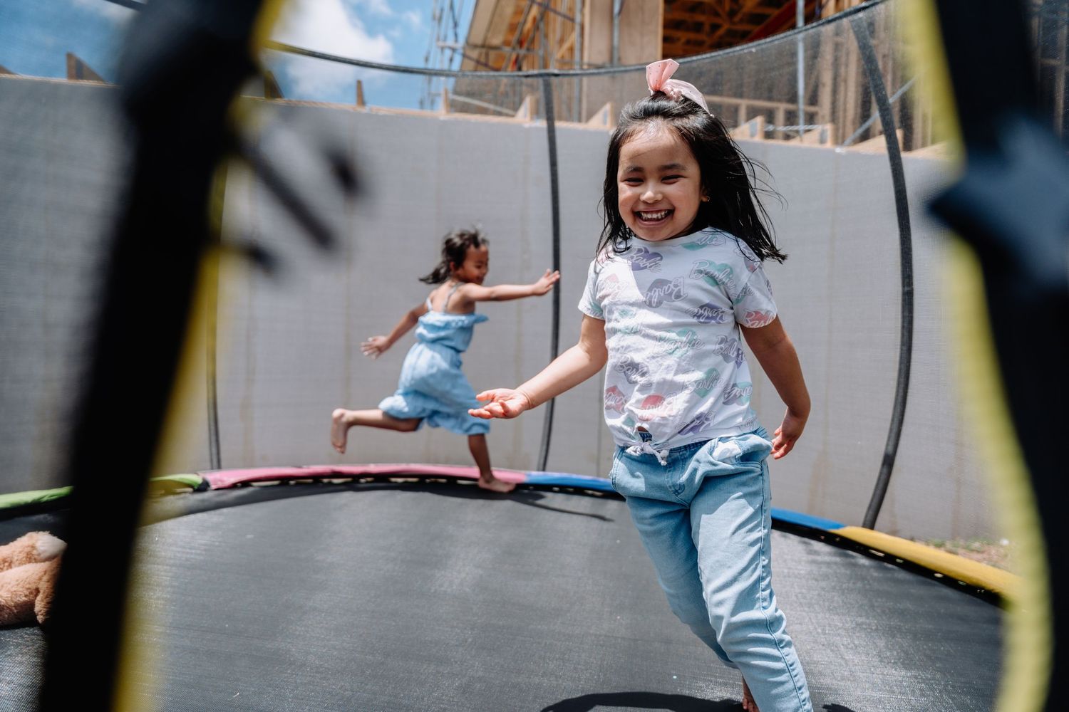 Children jumping and playing on a backyard trampoline on a sunny day.