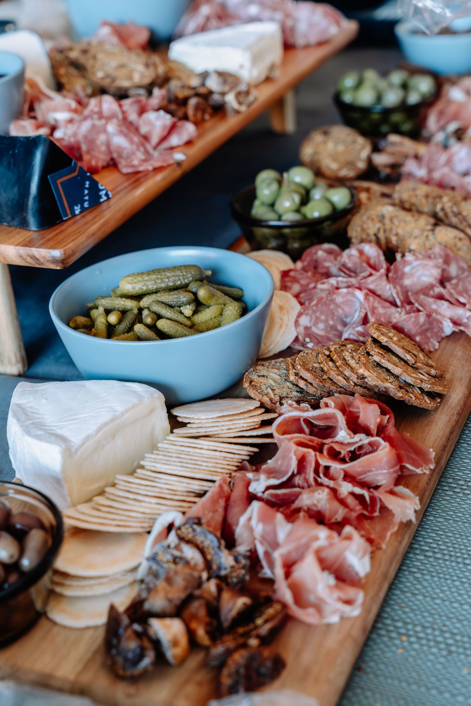 Wooden charcuterie board with assorted cured meats, pickles, crackers and cheeses arranged for entertaining.