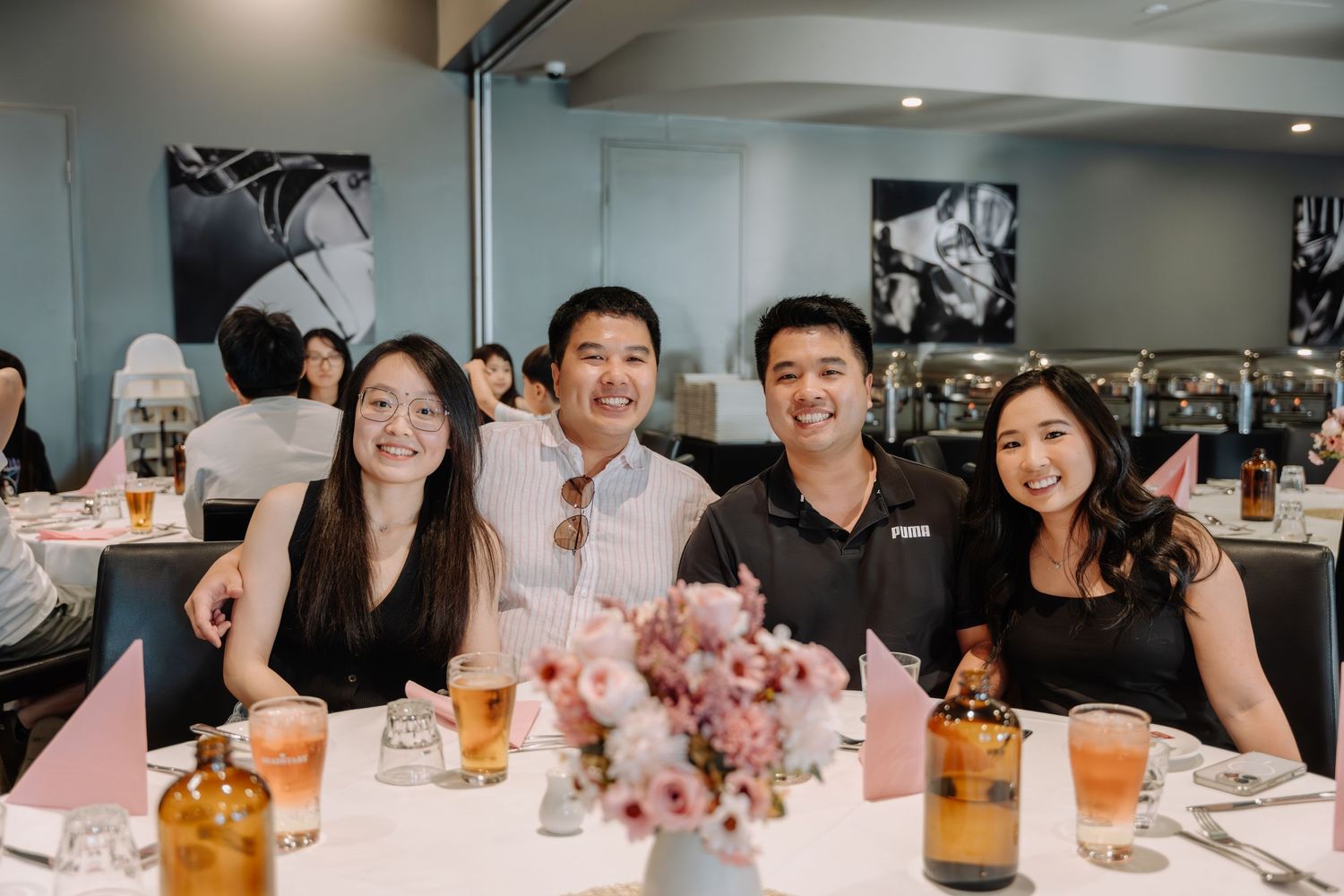 A panoramic view of people gathered around a dining table with bottles and glasses during a social event.