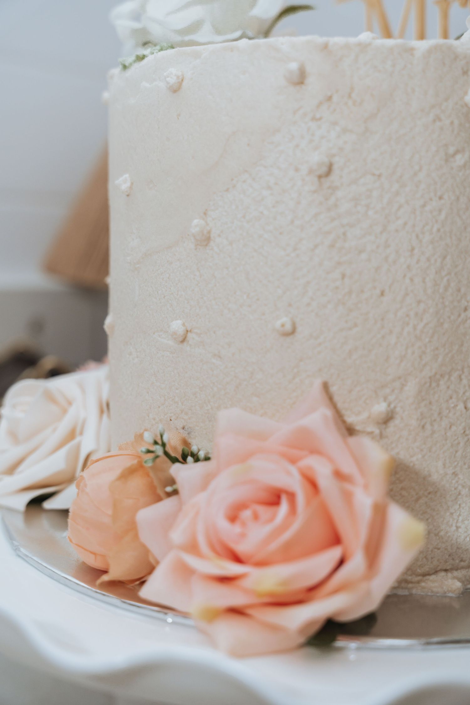 A close-up sequence of delicate peach-colored roses adorning the side of a white wedding cake.