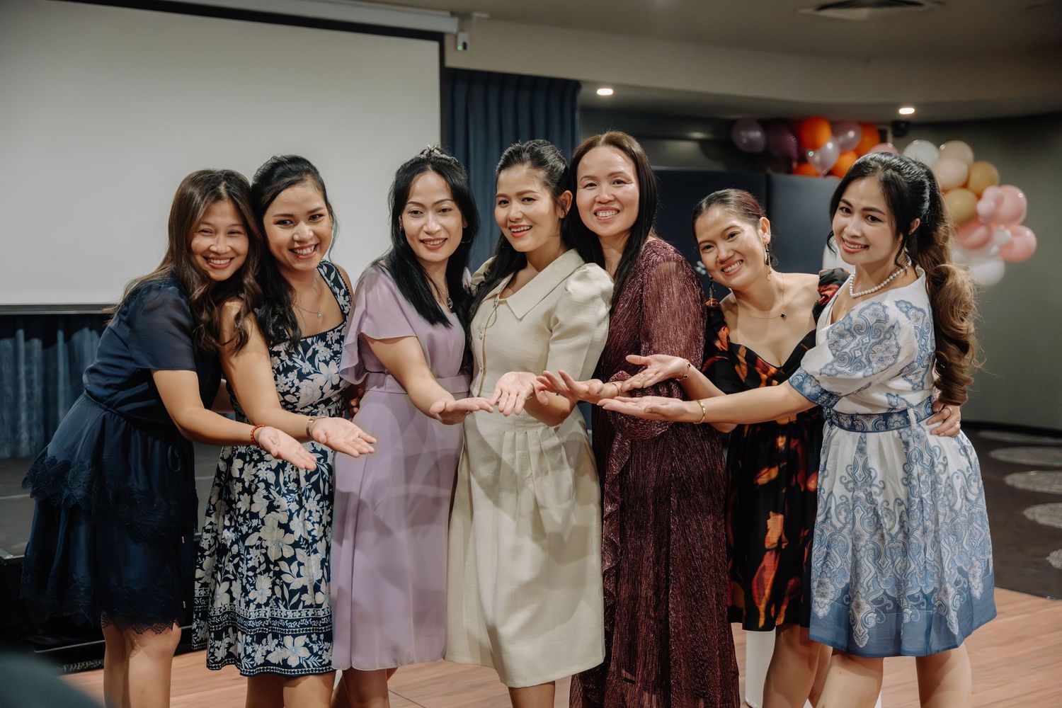 A group of bridesmaids in purple and blue dresses pose together during a wedding celebration.