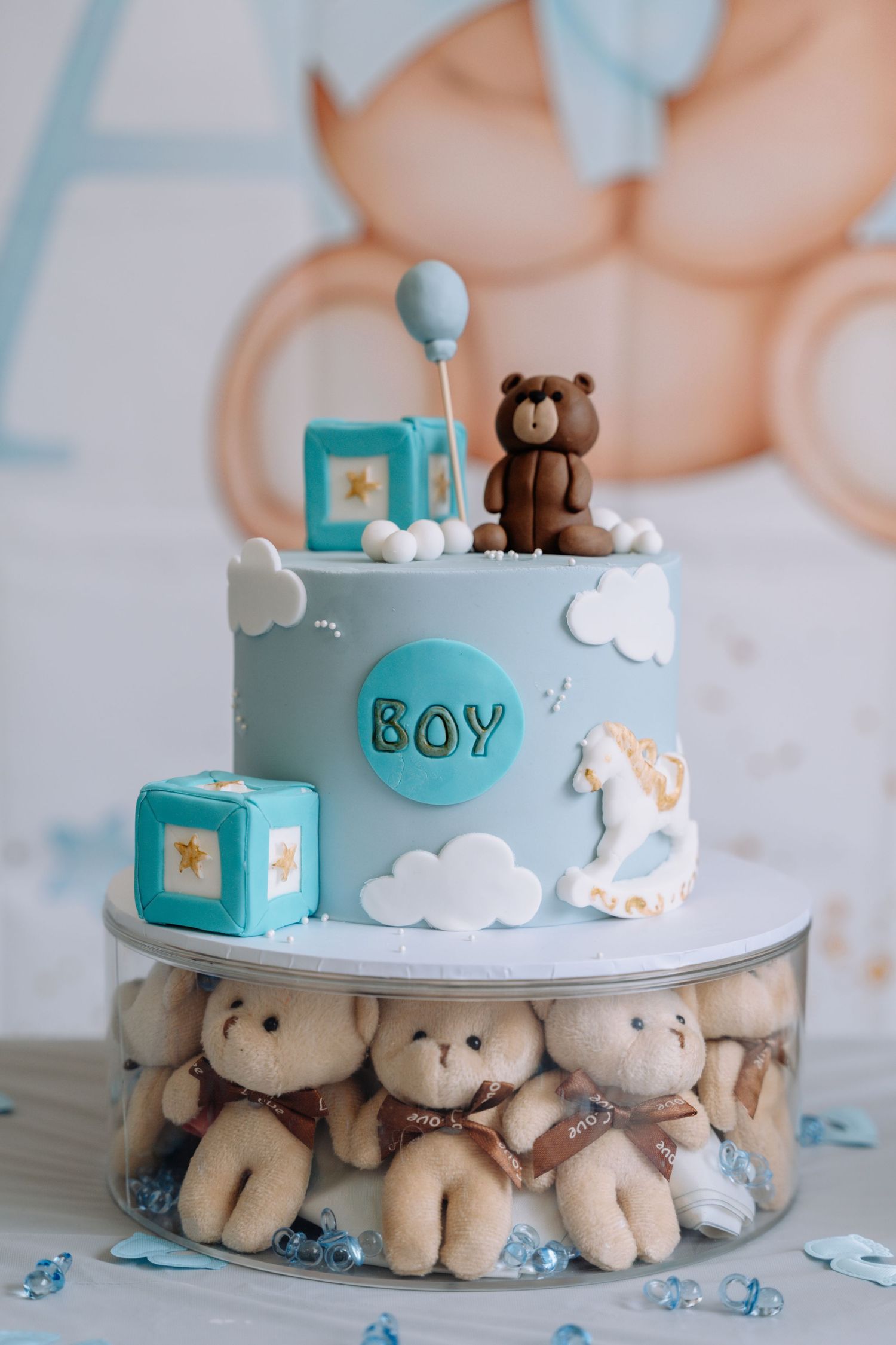 Baby shower cake decorated in light blue with teddy bears and clouds on a white cake stand.