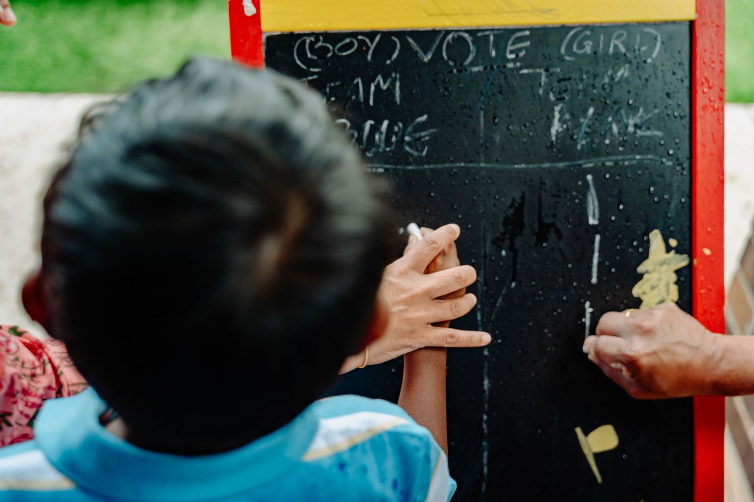 Students writing on a chalkboard in a classroom setting.