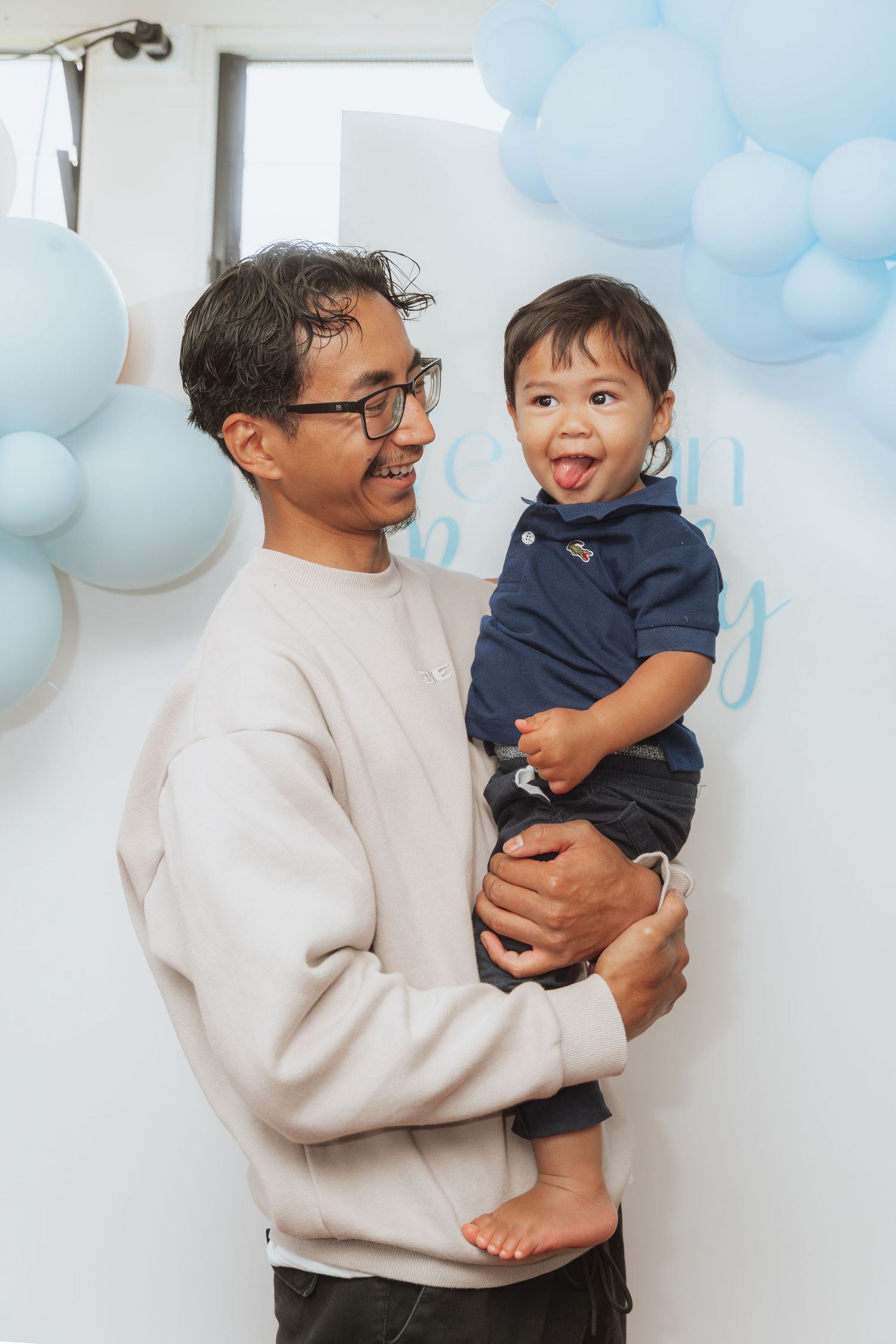 A series of candid photos showing a person in a cream sweater holding and playing with a toddler in navy blue clothing.