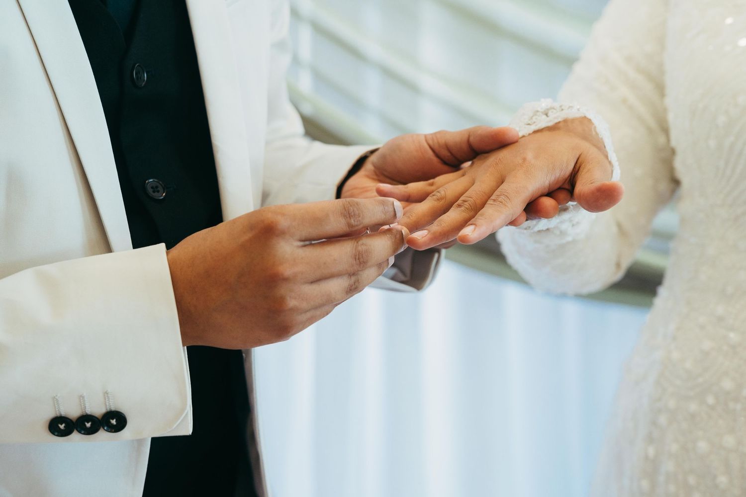 Close-up of a groom placing a wedding ring on his brides finger during a wedding ceremony.