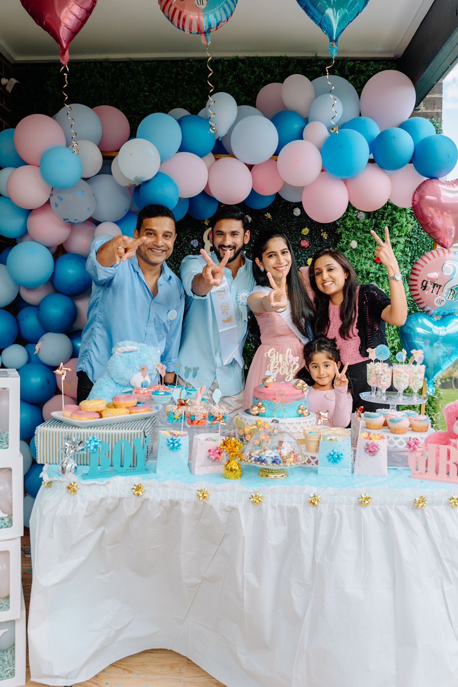 Party table decorated with blue and pink balloons and white tablecloth for a gender reveal celebration.