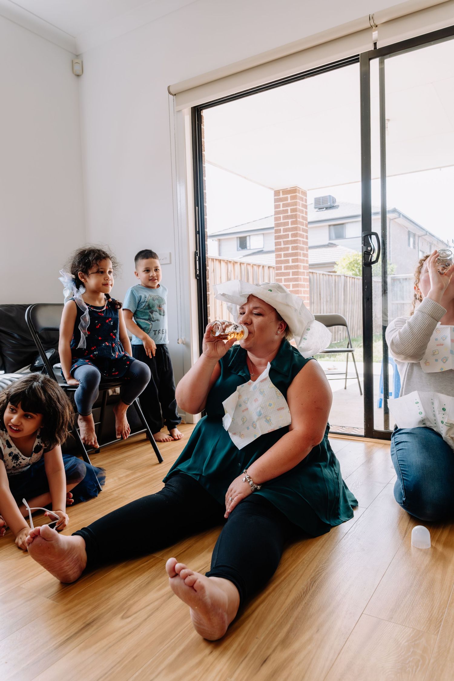 People sitting on the floor playing party games in a bright room with sliding glass doors.