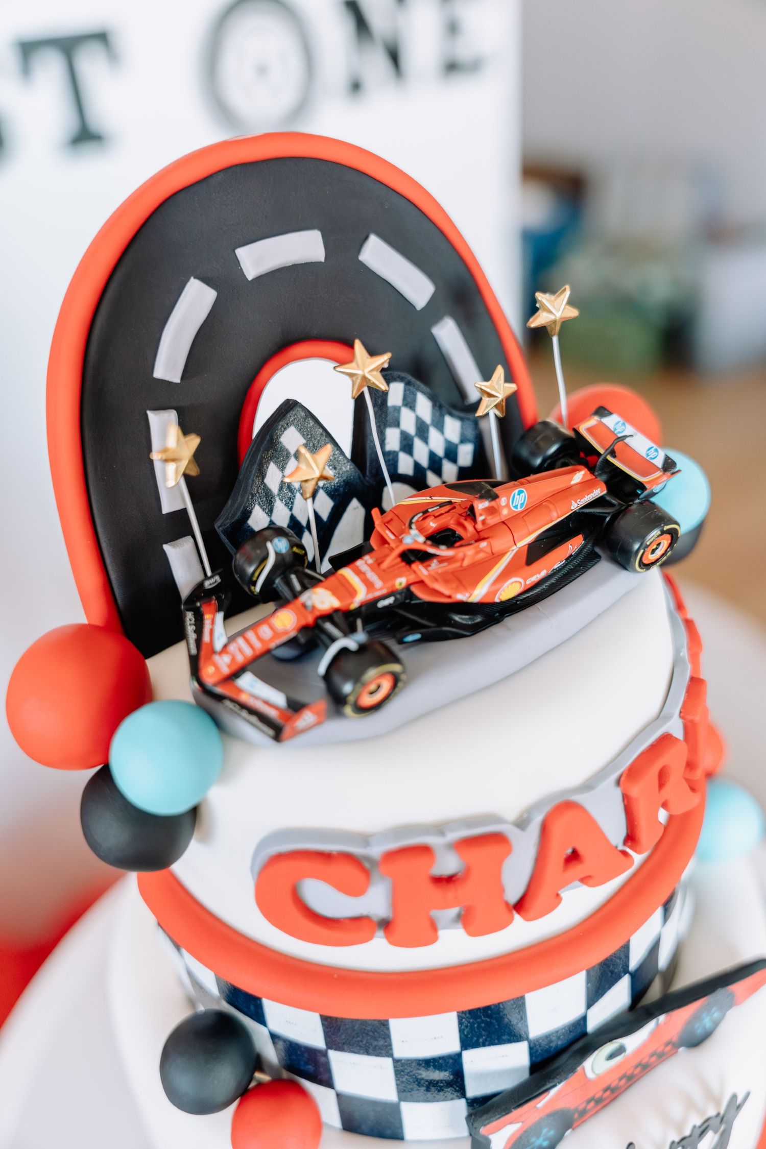 Close-up details of a racing car themed birthday cake decorated with checkered flags and orange accents.