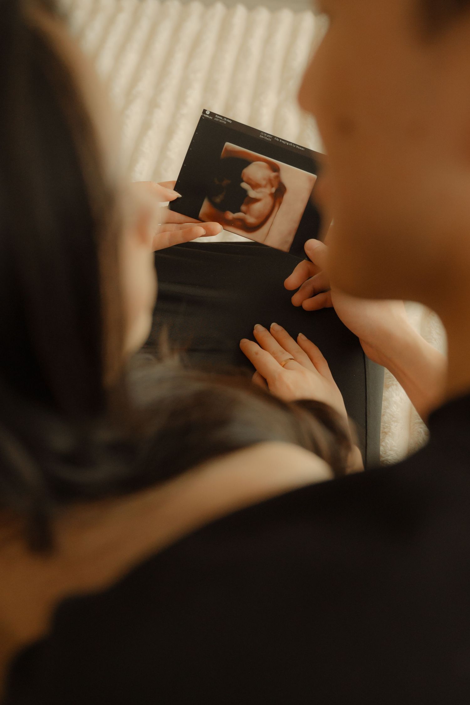 Hands holding a black book or journal in warm lighting with striped background patterns.