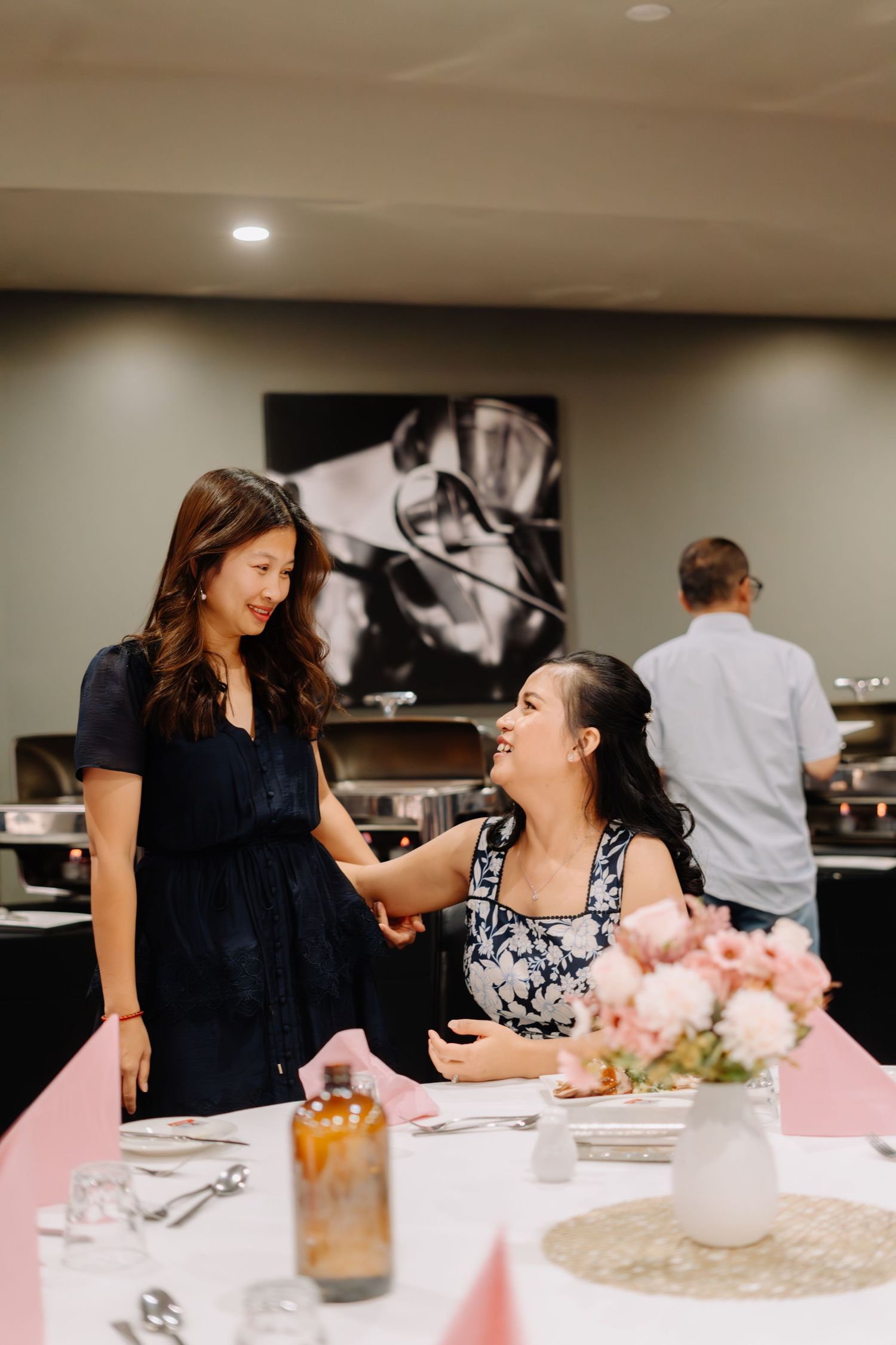 Two people share a joyful moment at a party with pink table settings and floral centerpieces.