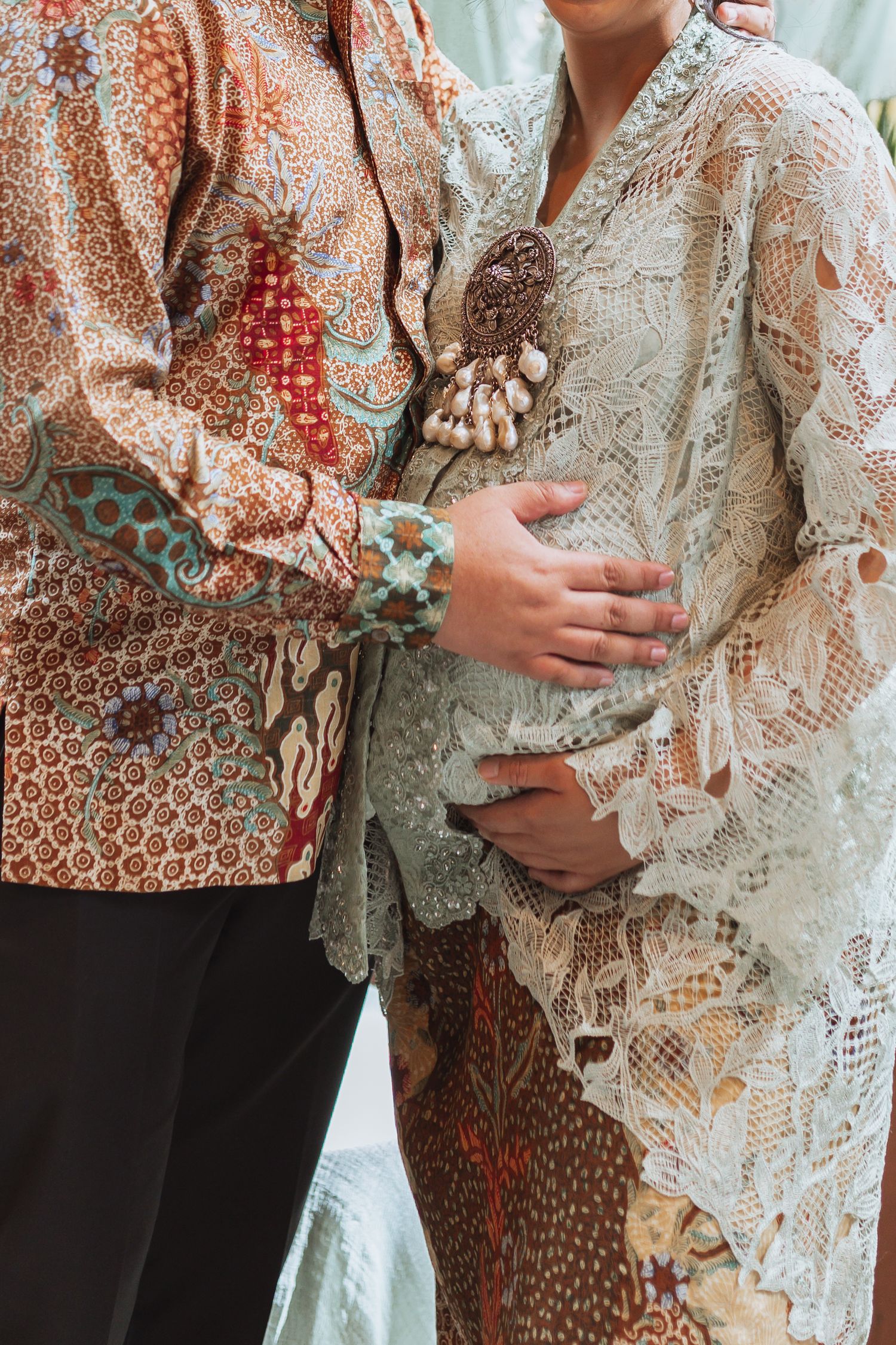 Close up of people wearing traditional batik and lace clothing in warm earth tones.