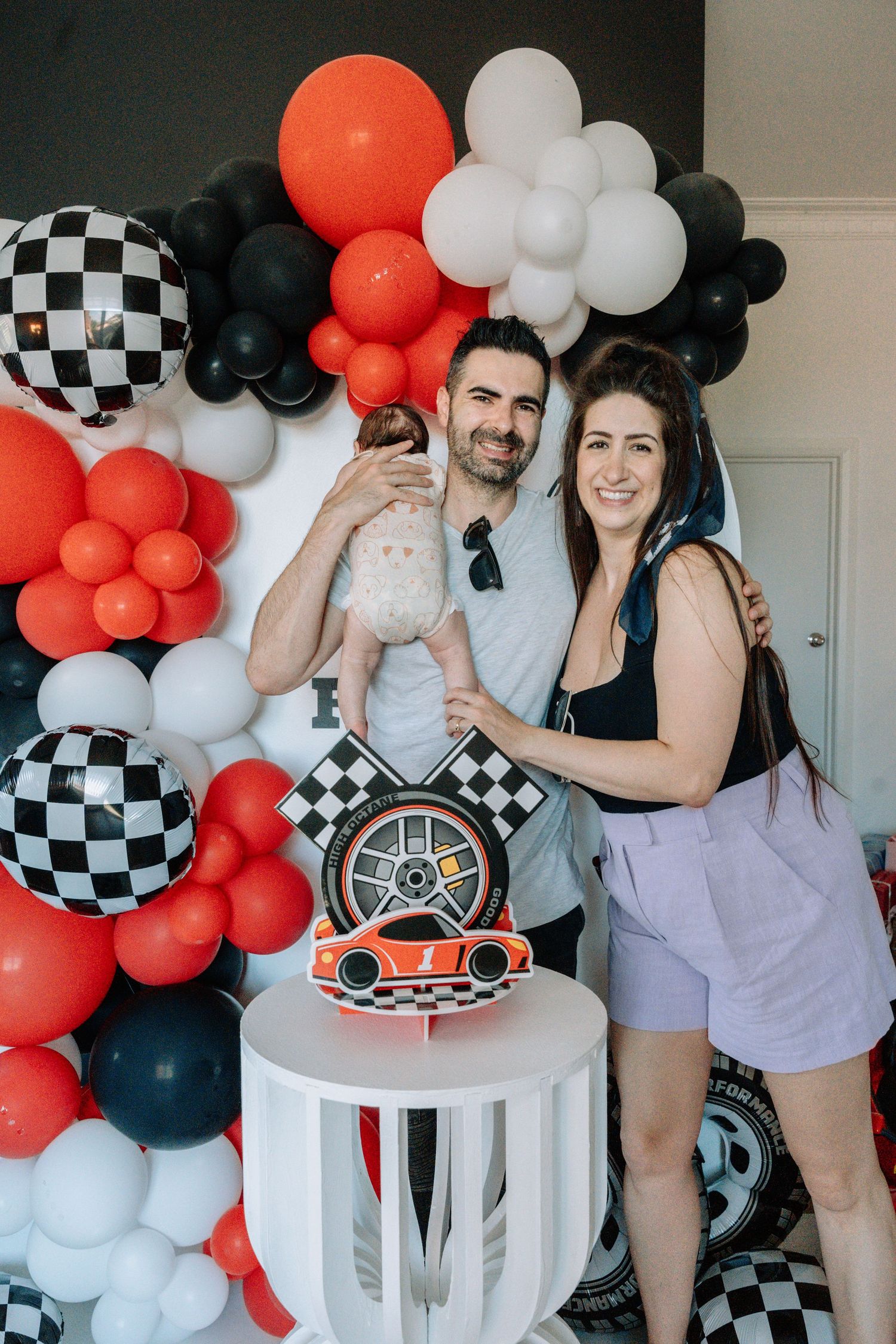Racing themed party setup with black, white and red balloon arch and decorative elements.