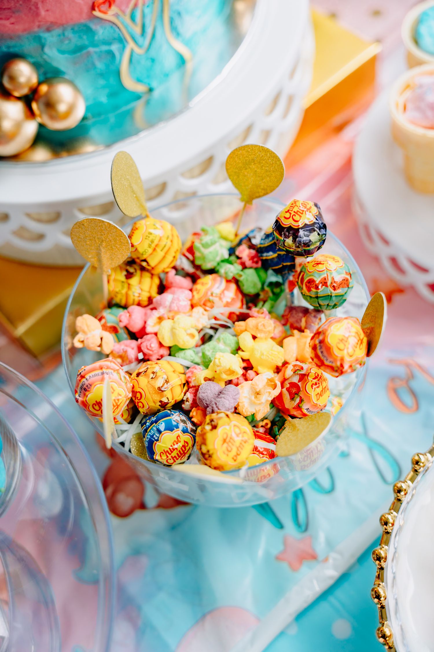 Gourmet rainbow popcorn served in elegant clear bowls with gold accents at a celebration.
