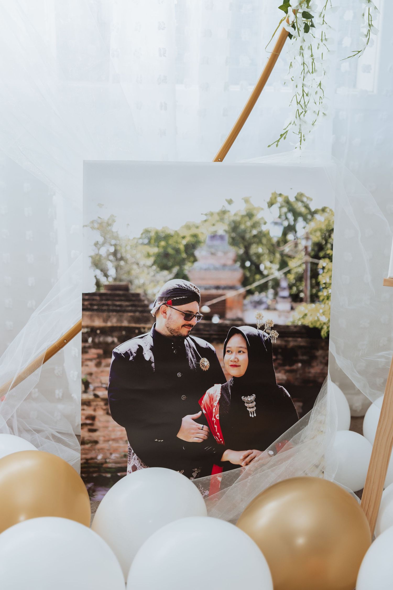 Romantic outdoor wedding scene with flowing white veil and gold balloons creating an ethereal atmosphere.