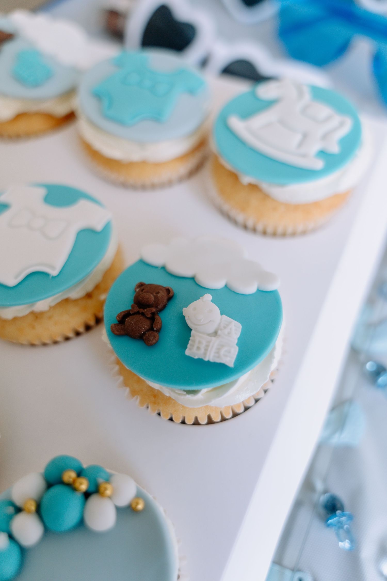Turquoise and white cupcakes decorated with baby-themed fondant toppers.