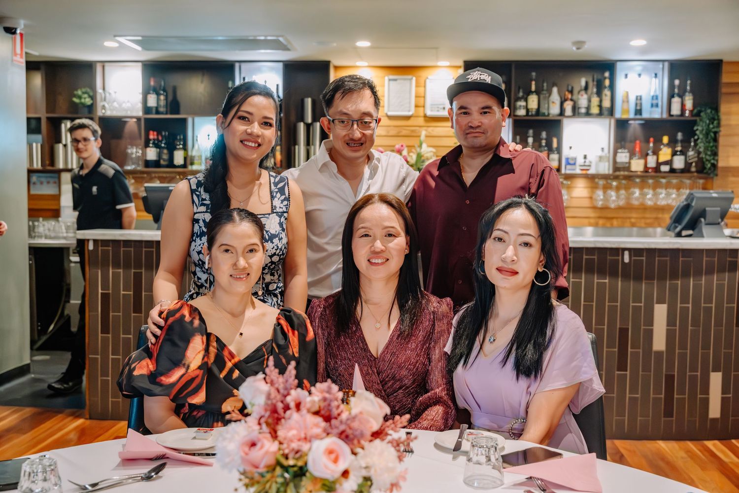 A group enjoying a meal together at a restaurant table with drinks and plates of food.