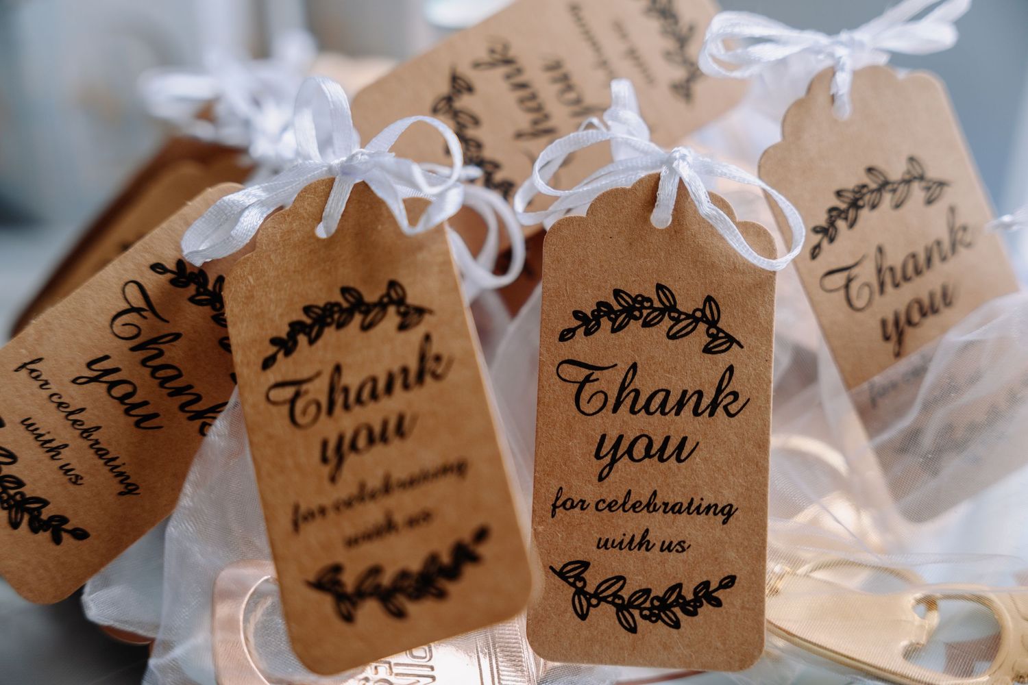 Brown kraft paper gift tags with 'Thank You' text and decorative wreath designs tied with white ribbon bows.