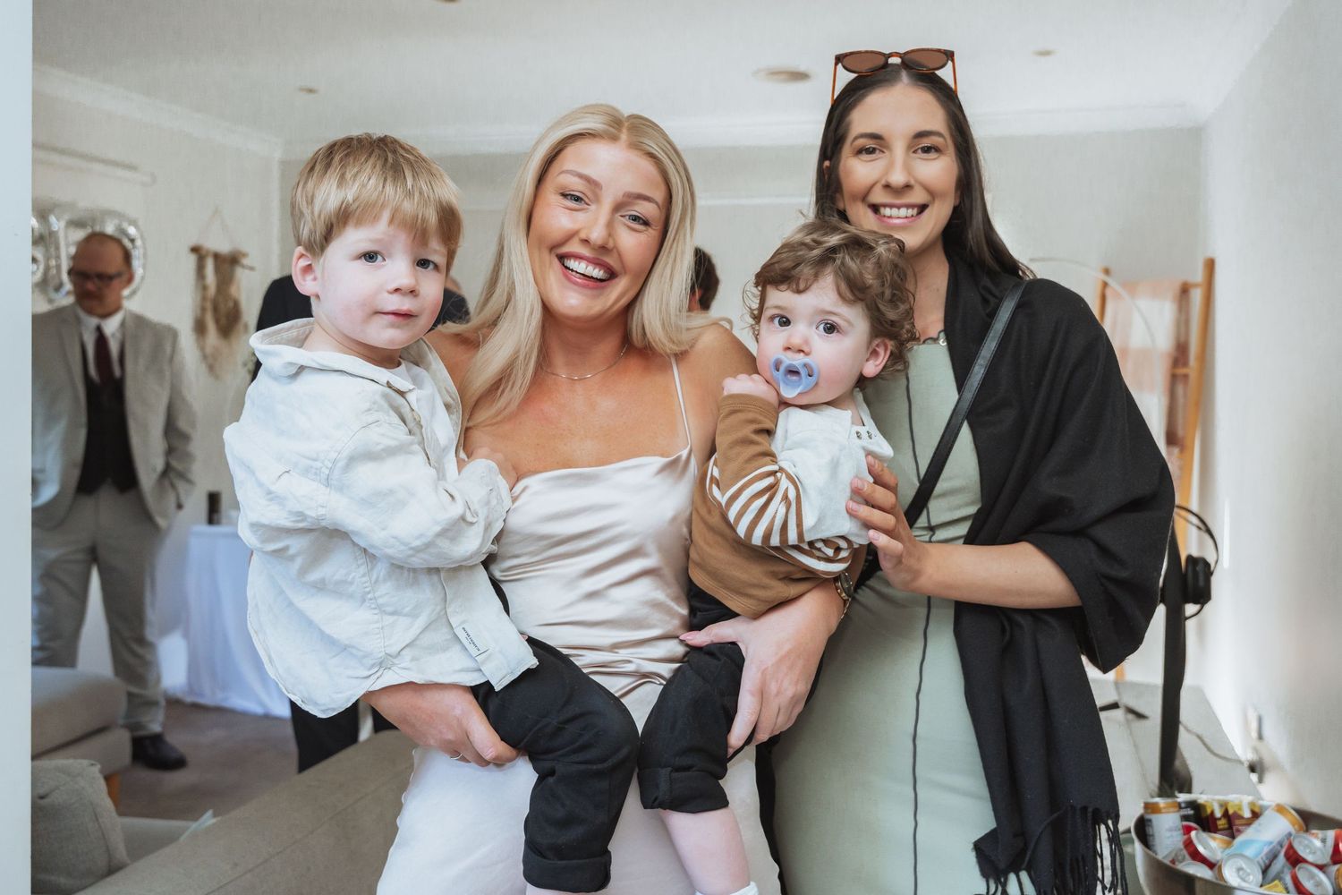 A candid group photo showing adults holding young children at an indoor gathering.
