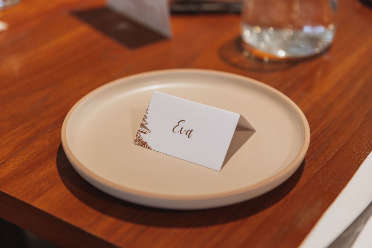 A small white card with the word 'Egg' sits on a cream colored plate atop a wooden table.