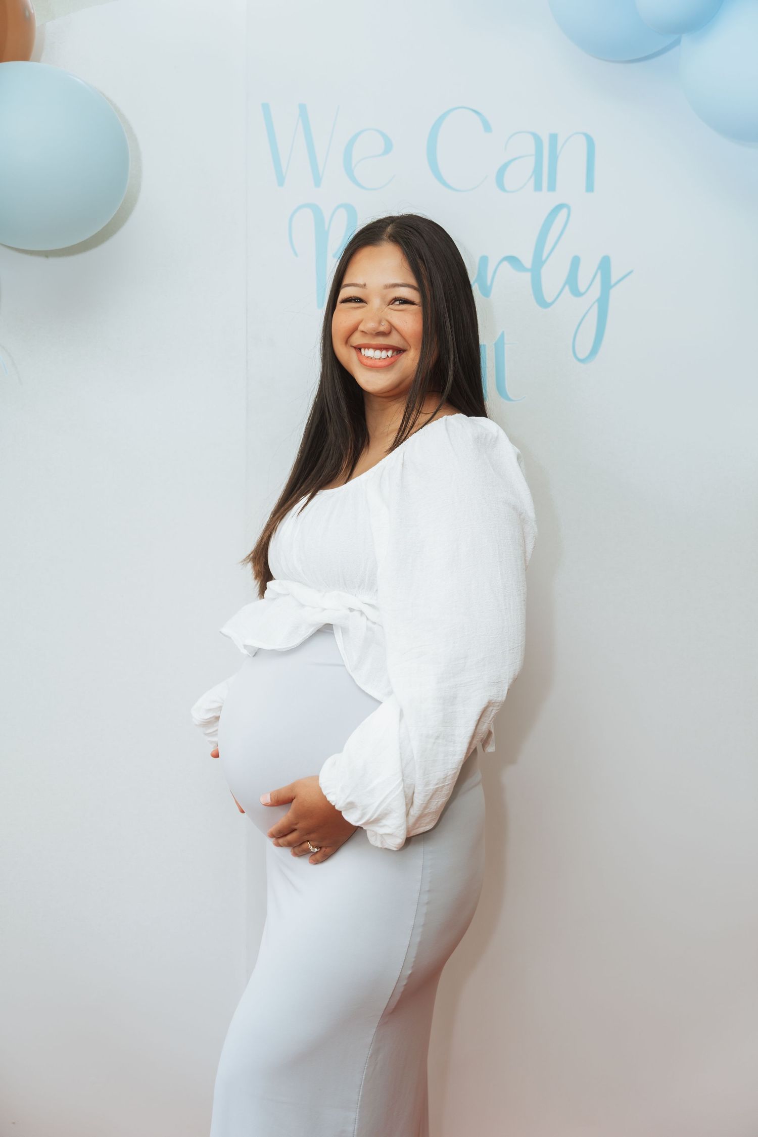 A series of pregnancy announcement photos showing someone in a white dress posing against a light blue and white backdrop.