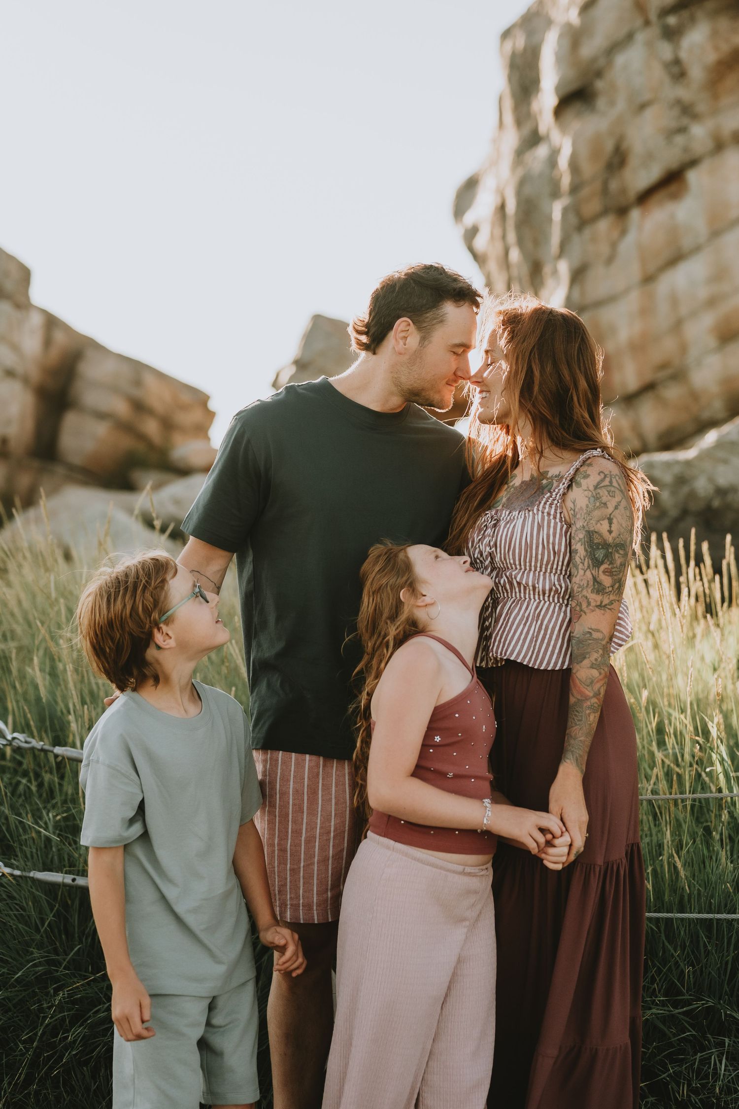 Family of four sharing a tender moment together near rocky outdoor landscape at Okotoks Erratic.