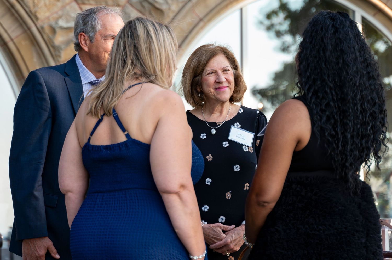Group of guests in formal wear socialize outdoors at an elegant evening networking event.
