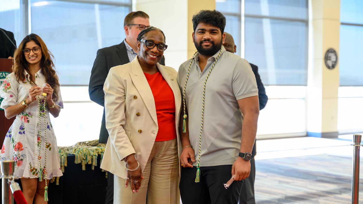 Two professionals smiling and posing together at a corporate event in a modern conference venue.