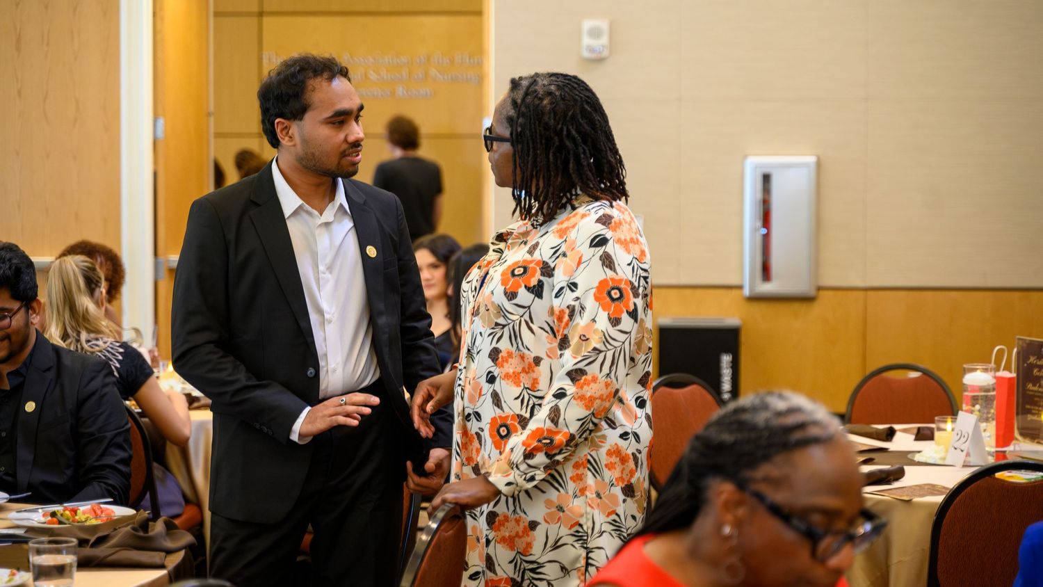 Two professionals engage in conversation at a networking event in a conference room setting.