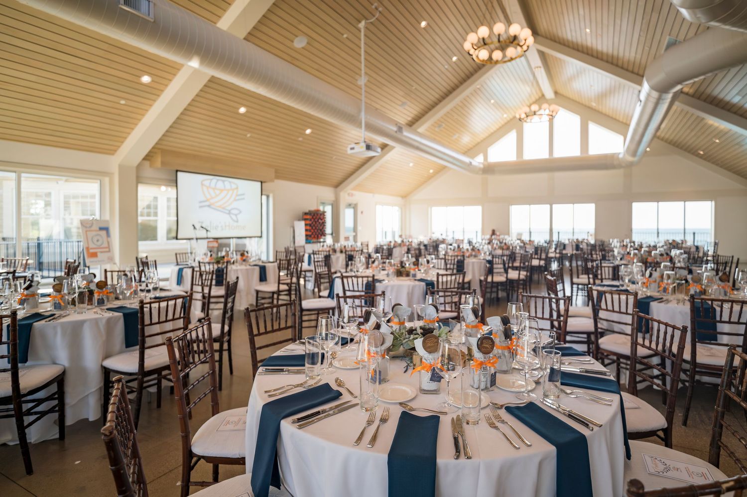 Elegant banquet hall set with white and navy tables for a formal dining event.