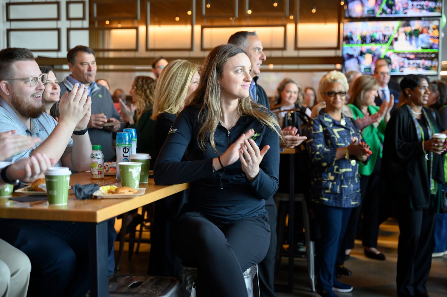 Employees applauding at a corporate gathering inside a modern restaurant venue.