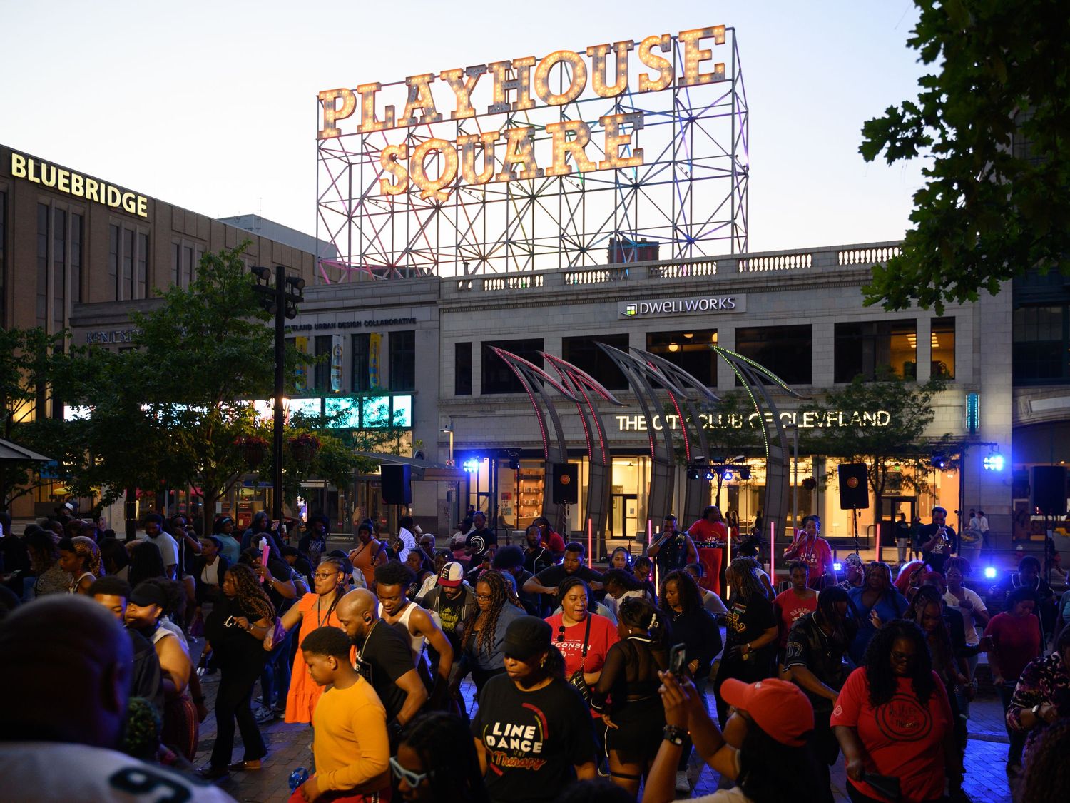 Crowd gathered outside Playhouse Square theater in Cleveland at dusk with bright marquee sign illuminated.