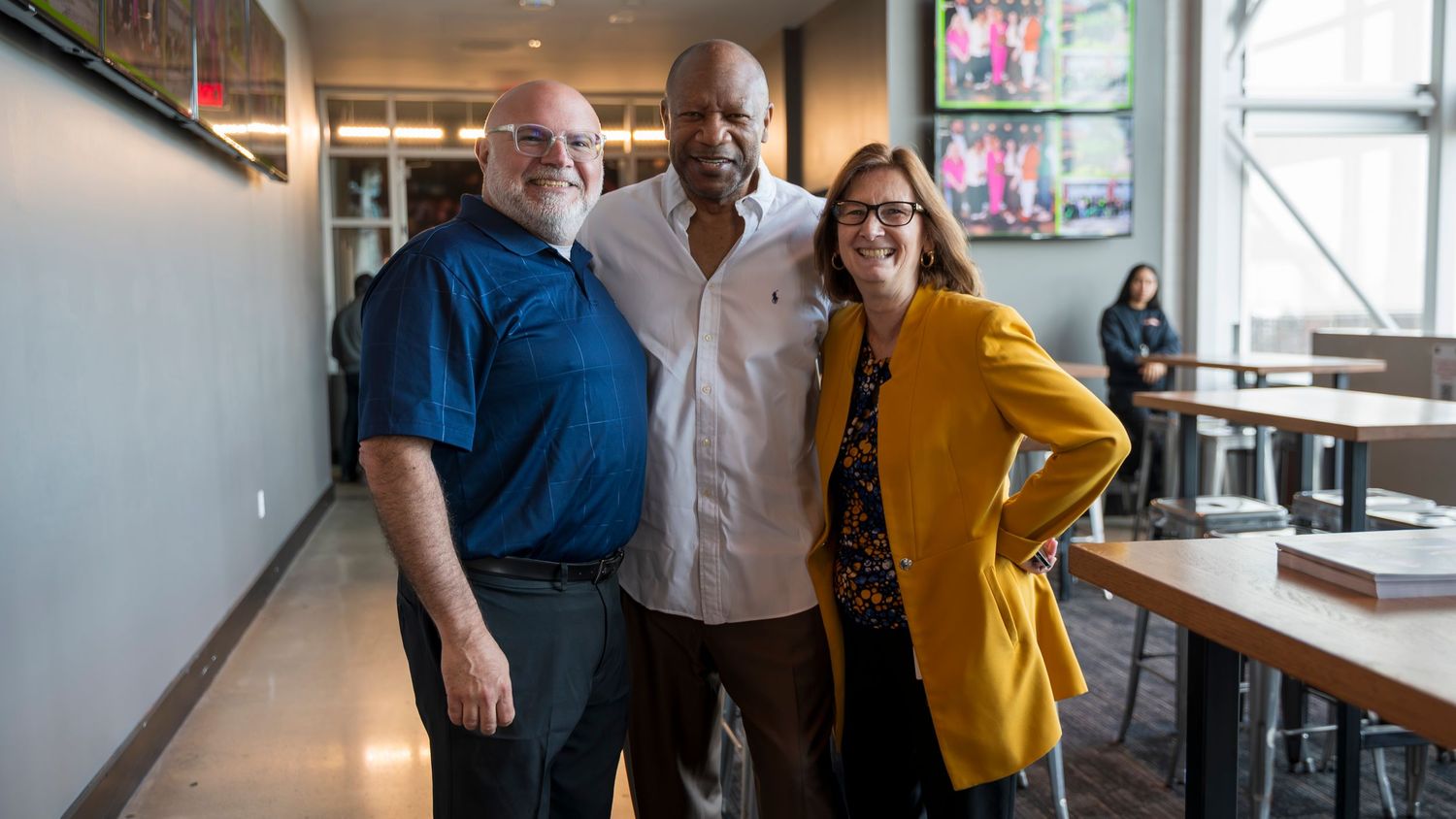 Two men and a woman smile together for a photo inside the cleveland browns stadium