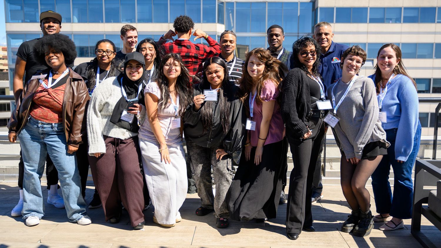 Diverse group of smiling students posing together outdoors on a sunny day at a university campus event.