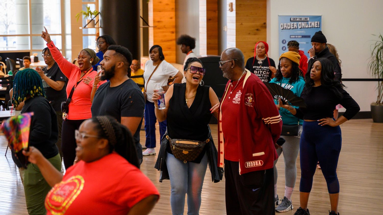 Diverse group of people dancing and celebrating at an indoor event, wearing red and casual attire.