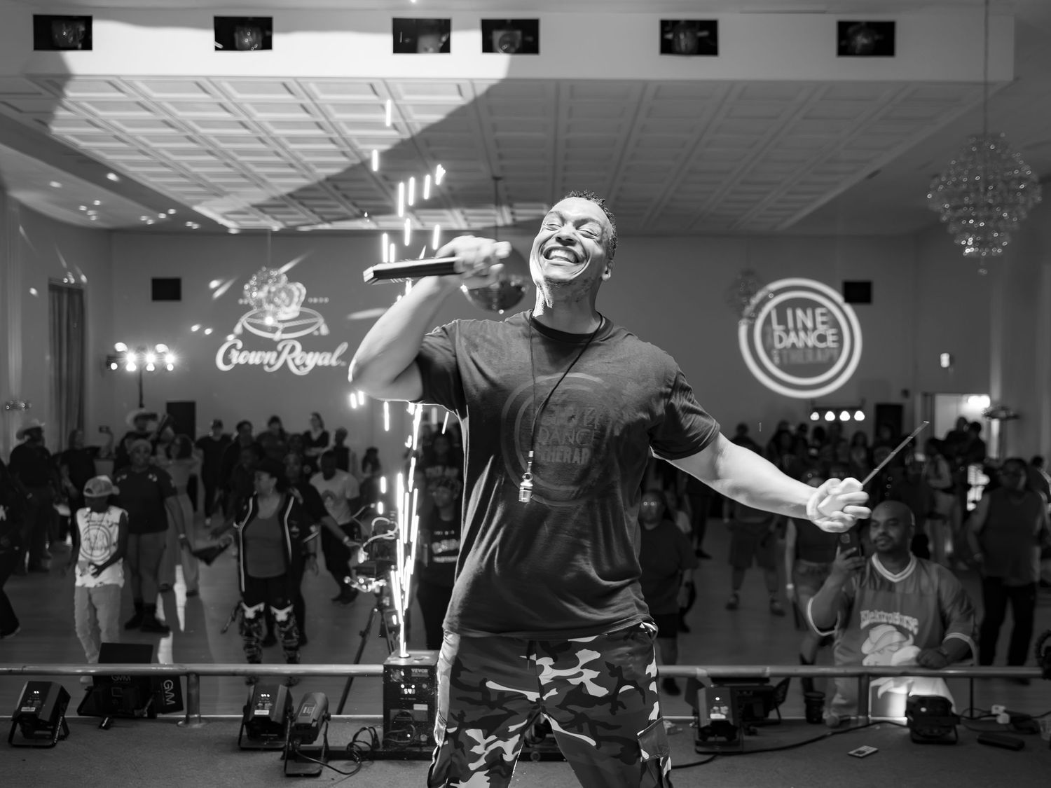 Black and white photo of an energetic male performer singing on stage at a Crown Royal sponsored event.